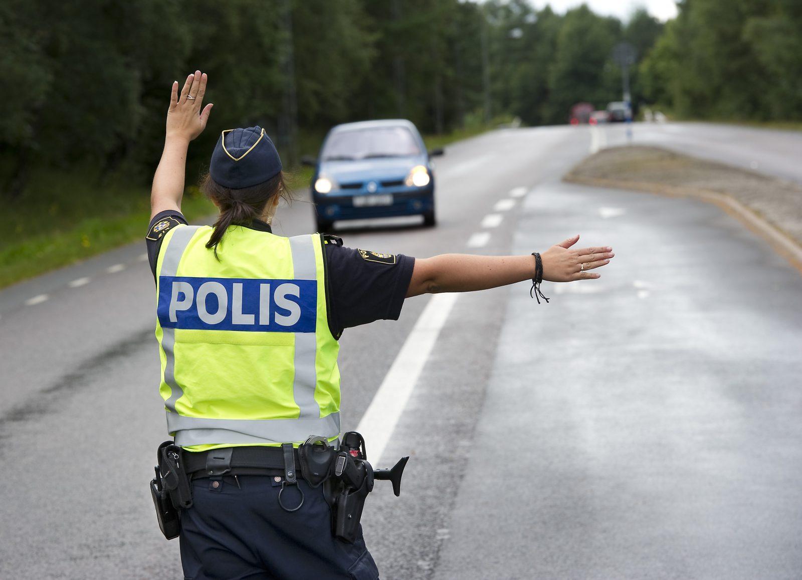 Polis som stoppar en bil på en väg.