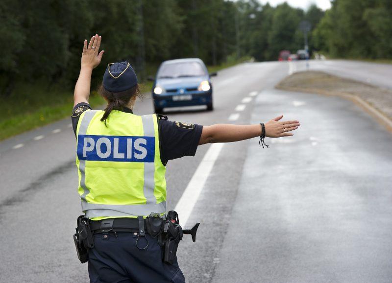 Polis som stoppar en bil på en väg.