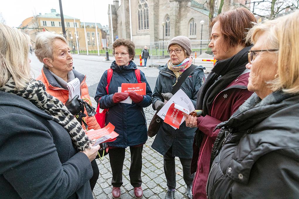 En grupp personer står ute på torg och diskuterar.