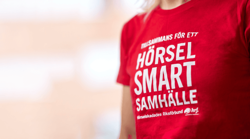 Röd t-shirt med texten: Tillsammans för ett hörselsmart samhälle.