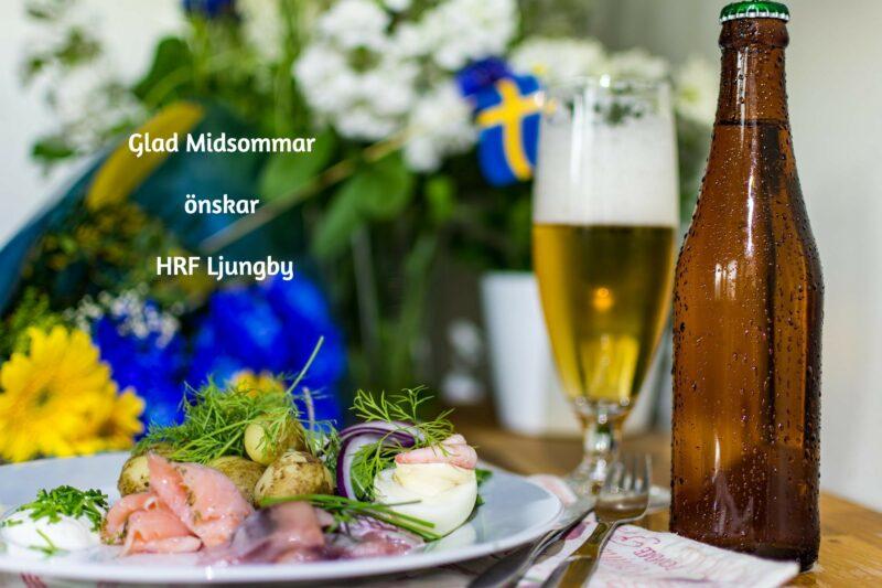 bild på midsommarlunch med kall dryck potatis och sil och lite midsommarblomster i bakgrunden