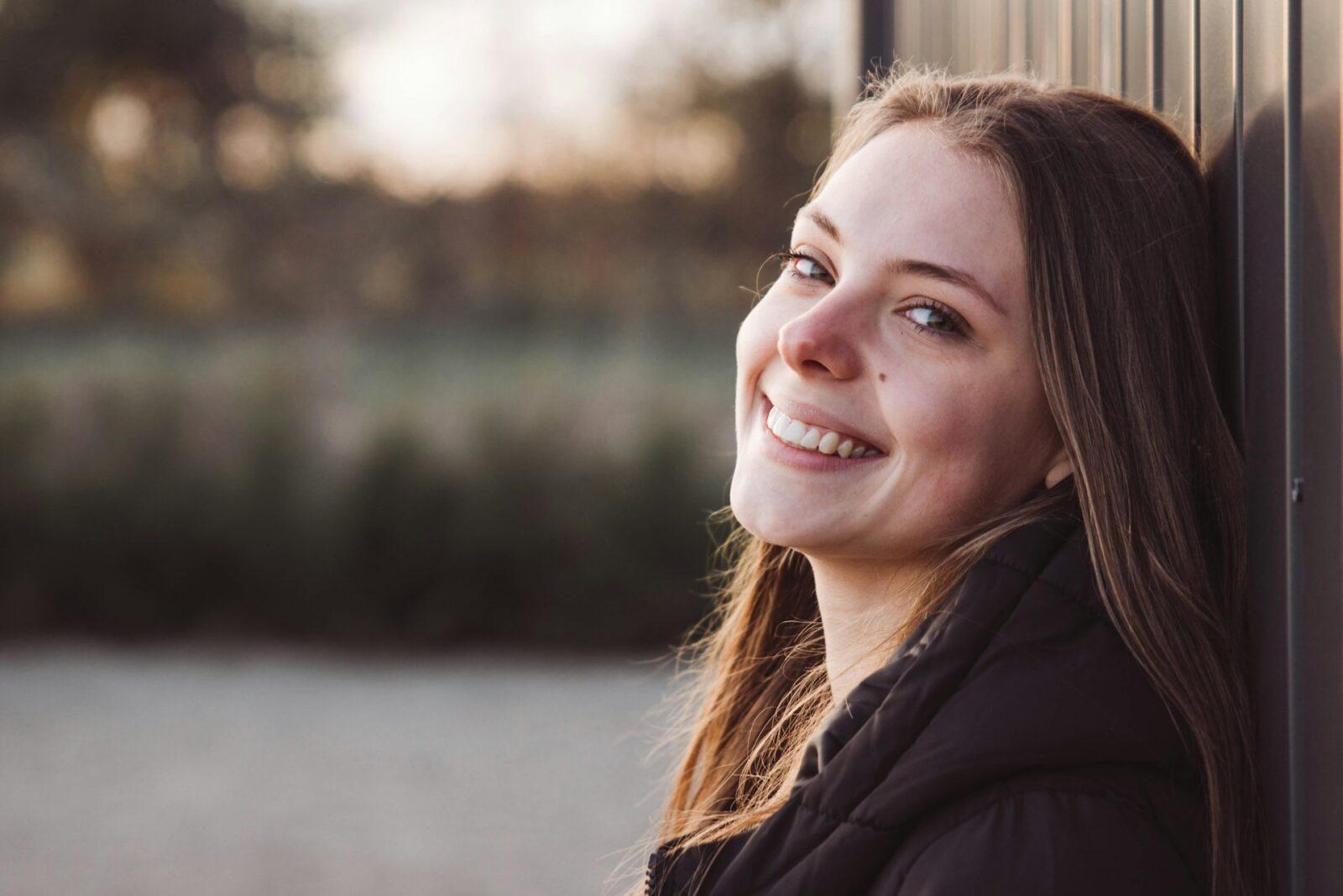 Leende kvinna vid husvägg