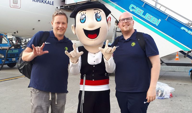 Två män från Svenska Dövidrottsförbundet står på var sin sida om en maskot för Deaflympics 2017.