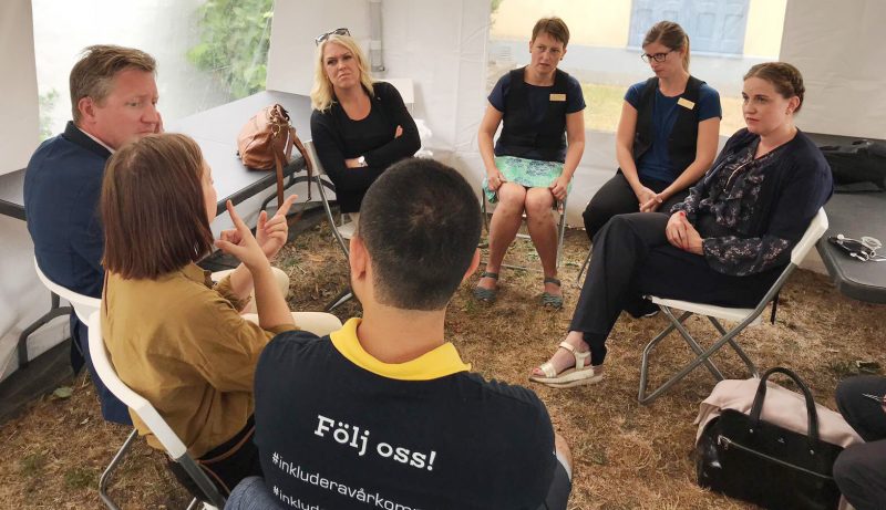 En grupp personer sitter i ring i ett tält. En av dem är Mattias Lundekvam, HRF, och en annan är statsrådet Lena Hallengren.