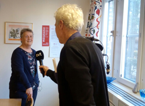 Reporter med ryggen mot kameran sträcker fram SVT-mikrofon mot Lena Thorén.