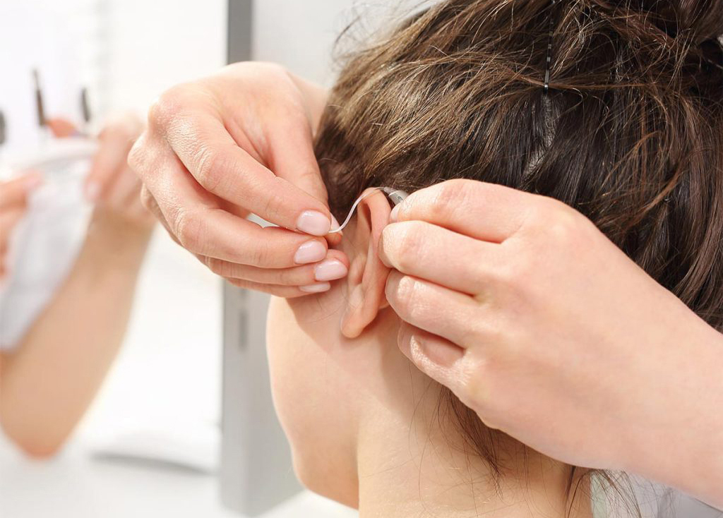 hörapparat sätts på kvinna med mörkt hår