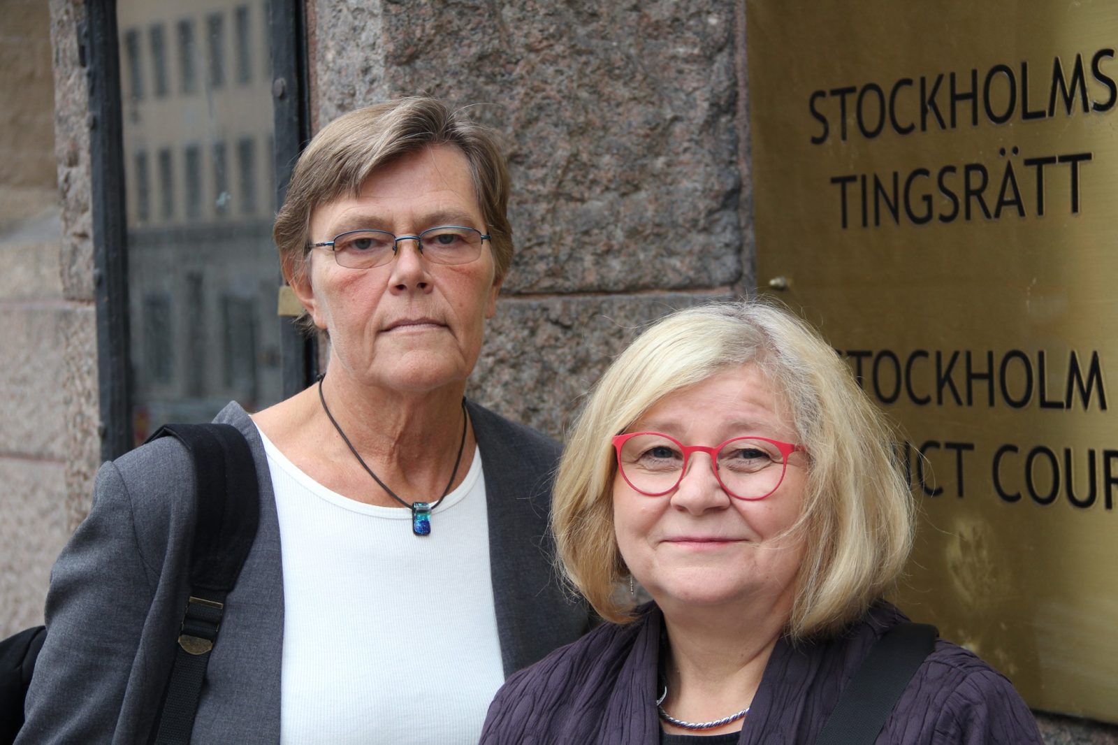 Två kvinnor framför skylt som säger "Stockholms tingsrätt".