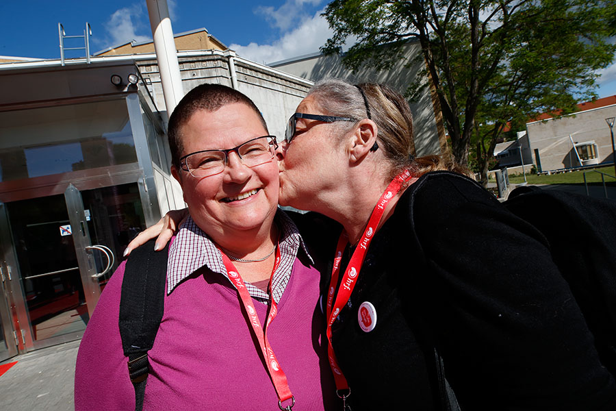 Två kvinnor med HRfs röda logoband om halsen. Den ena kvinnan ler mot kameran. Den andra pussar henne på kinden.