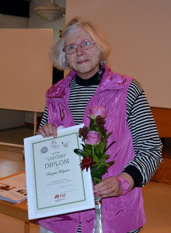 Birgitta Helgesson med diplom och blommor.