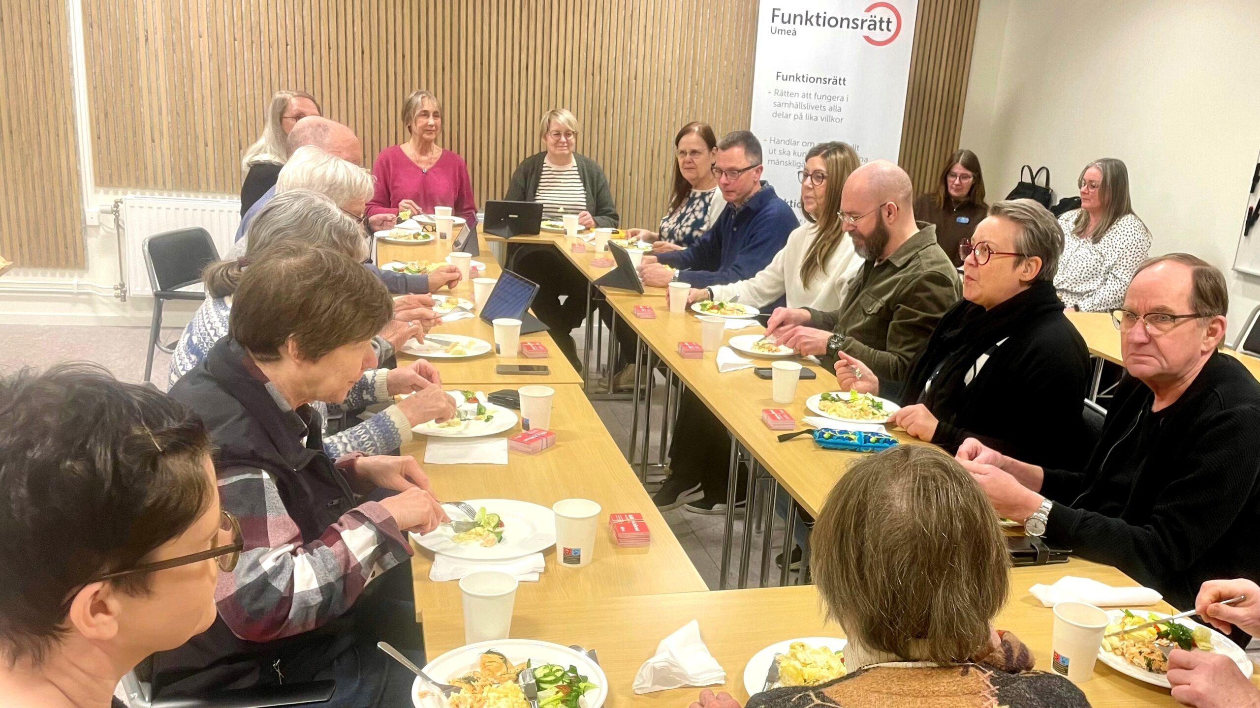 Bilden visar personer runt ett bord som äter.